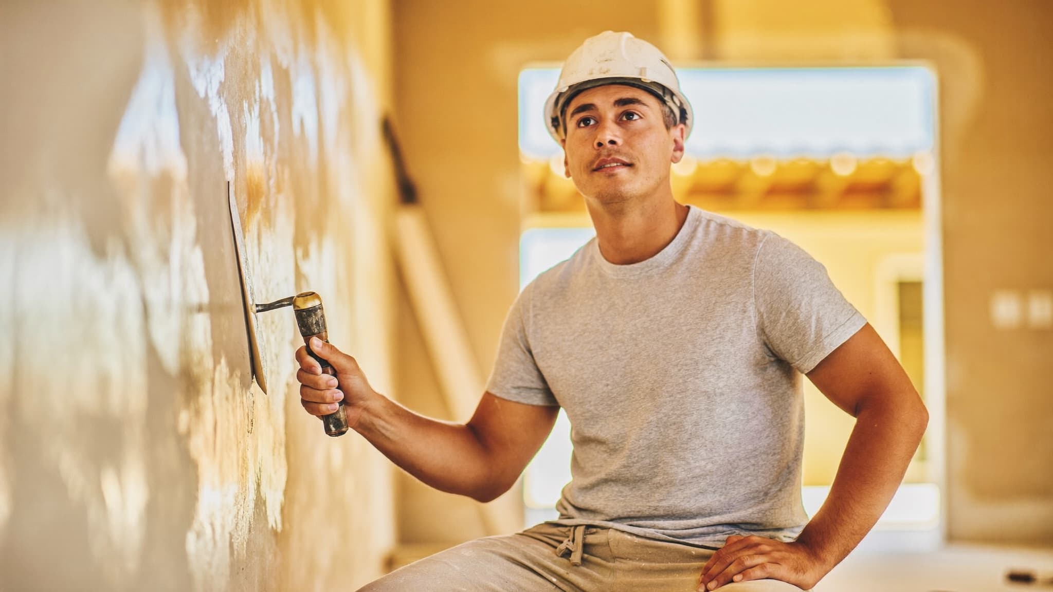 Operario enluciendo una pared durante su jornada en una vivienda en obra