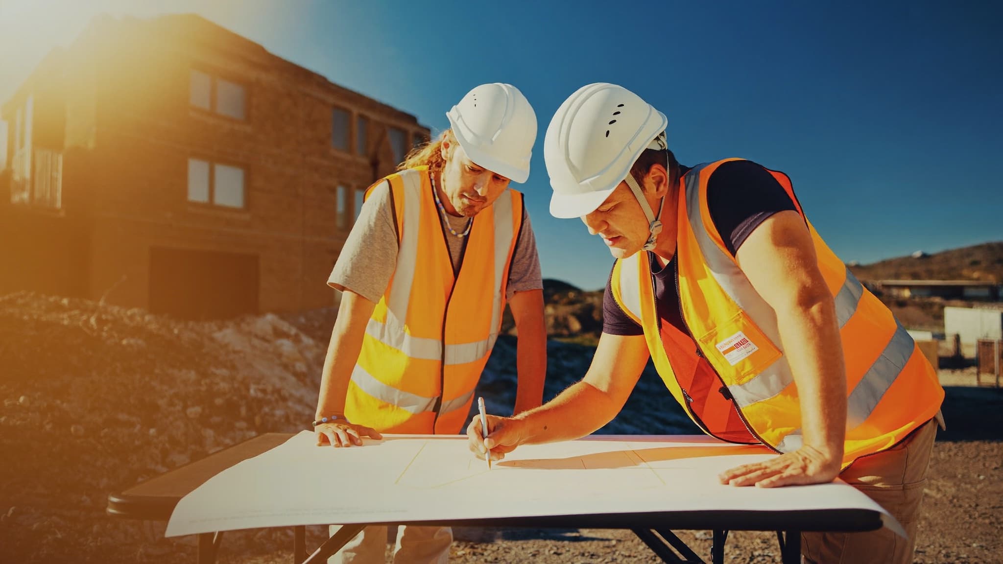 Dos técnicos revisando sobre el plano los costes de la obra a pie de obra